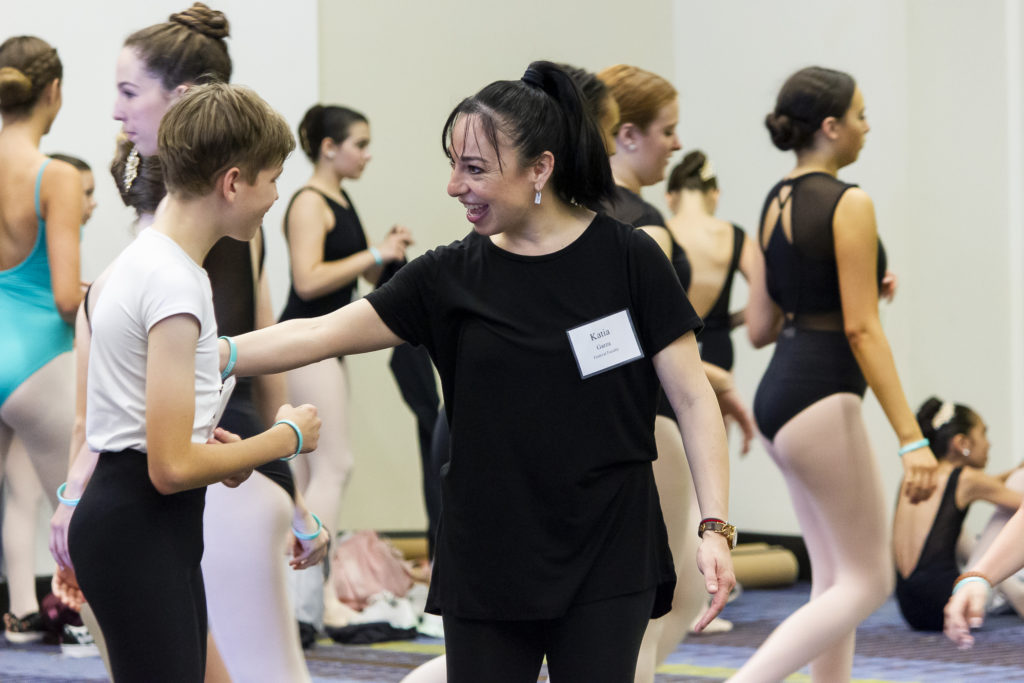 一位德赢vwin怎么样舞蹈老师微笑着与一名初中生的芭蕾舞男演员交谈。